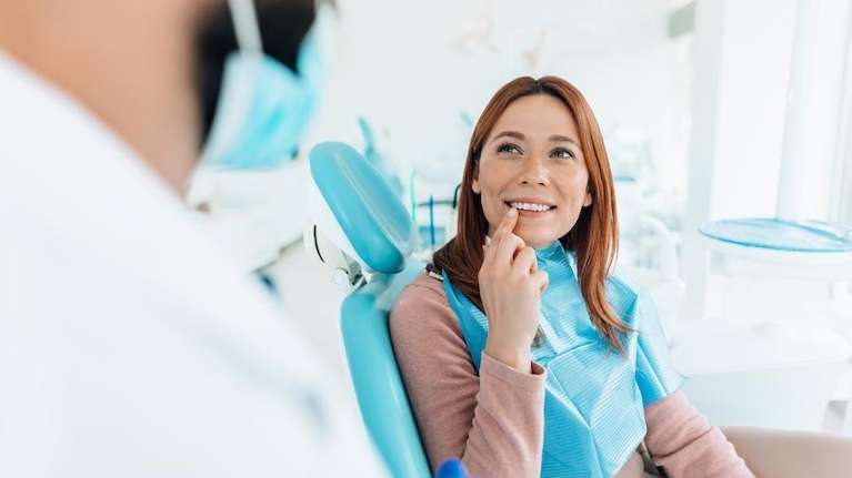 woman in dental chair talking to dentist about stages of gum disease